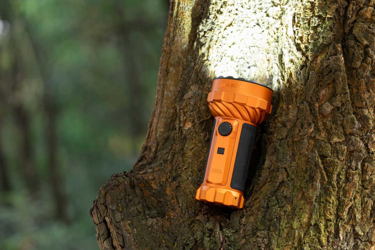 Olight Marauder 3 Orange outdoors against a tree