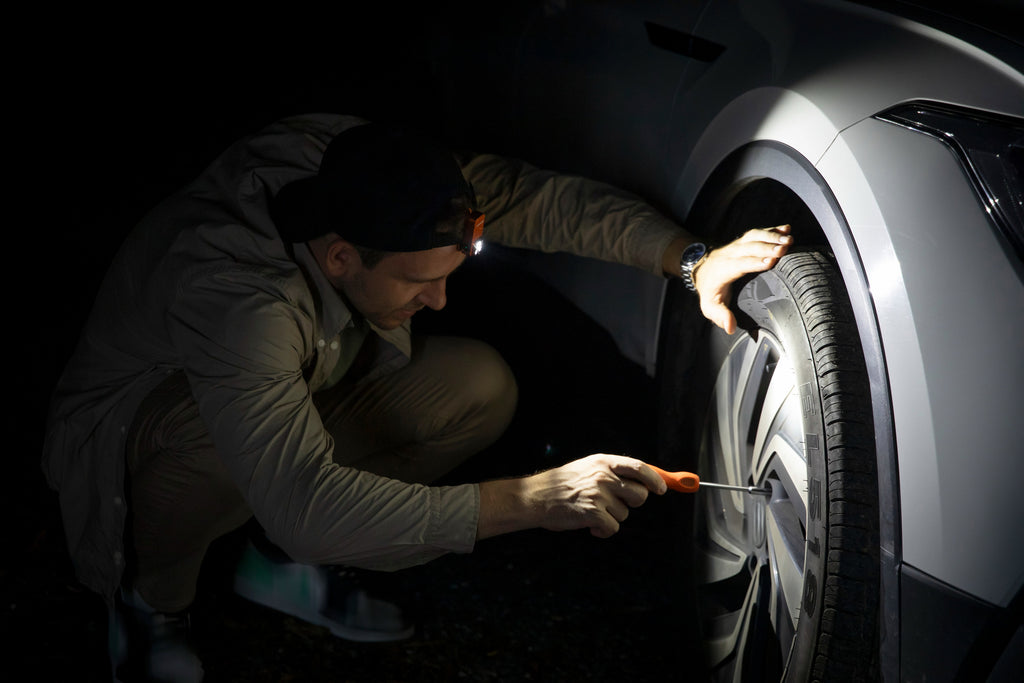 Olight Oclip 2 Pro illuminating a vehicle wheel during maintenance