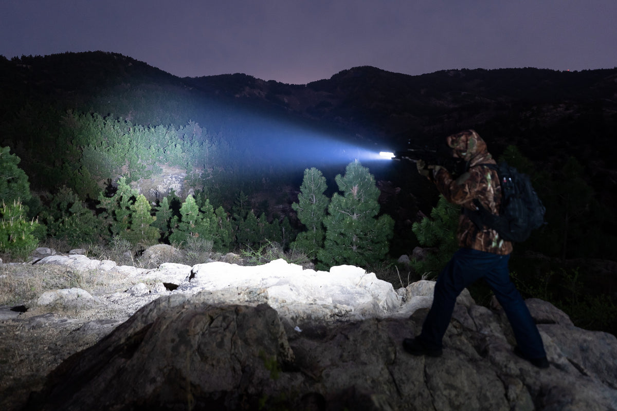 Olight Odin S projecting a long-range beam across an outdoor landscape at night