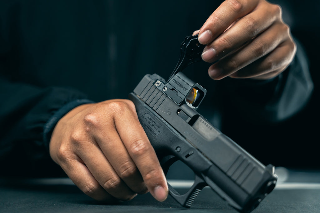 Olight OSIGHT SE red dot sight being adjusted on a mounted handgun